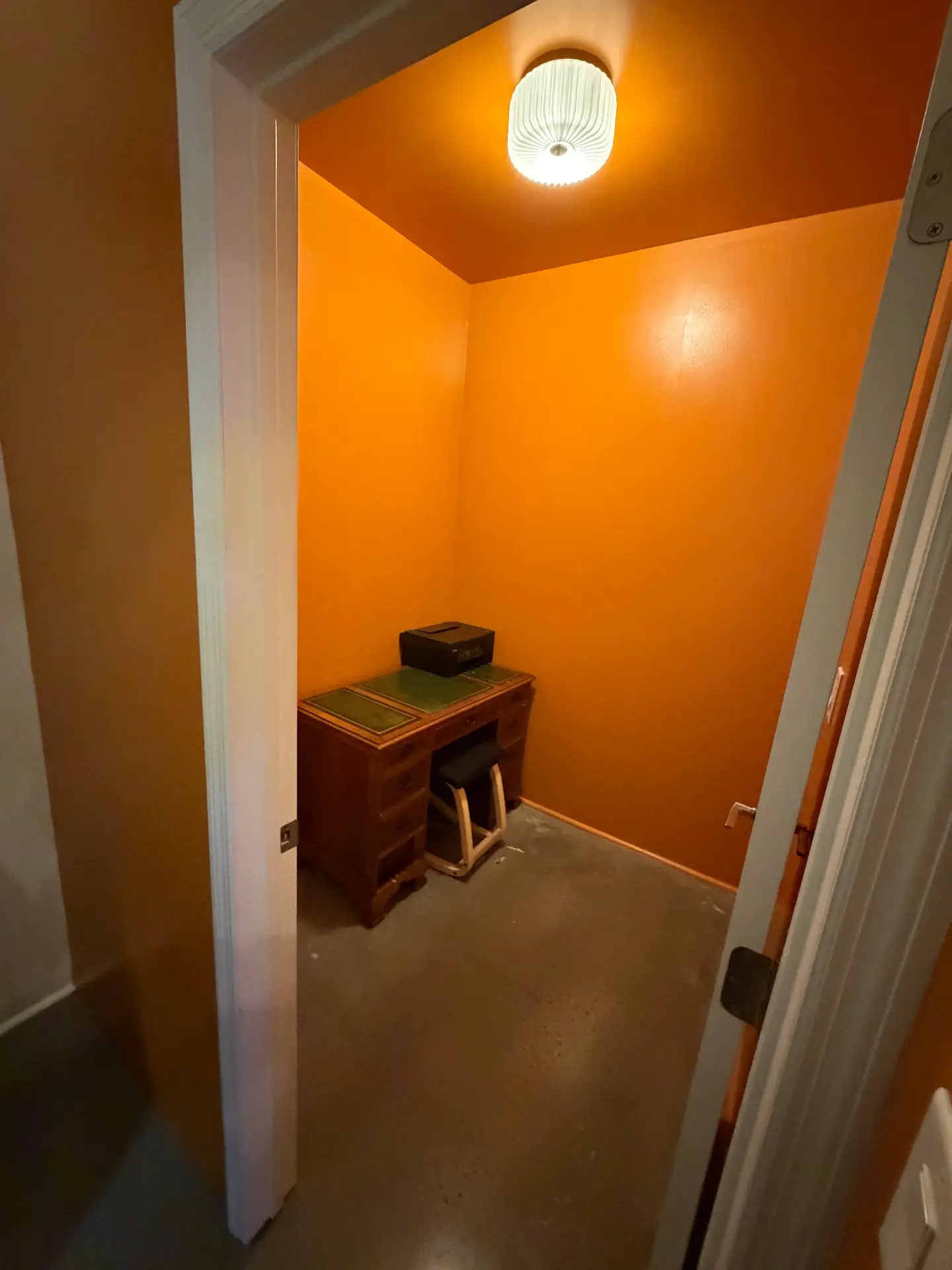 The Orange Room private office space at RISE Hub Brooklyn featuring a classic leather-top desk, chair, and a private closing door for remote workers