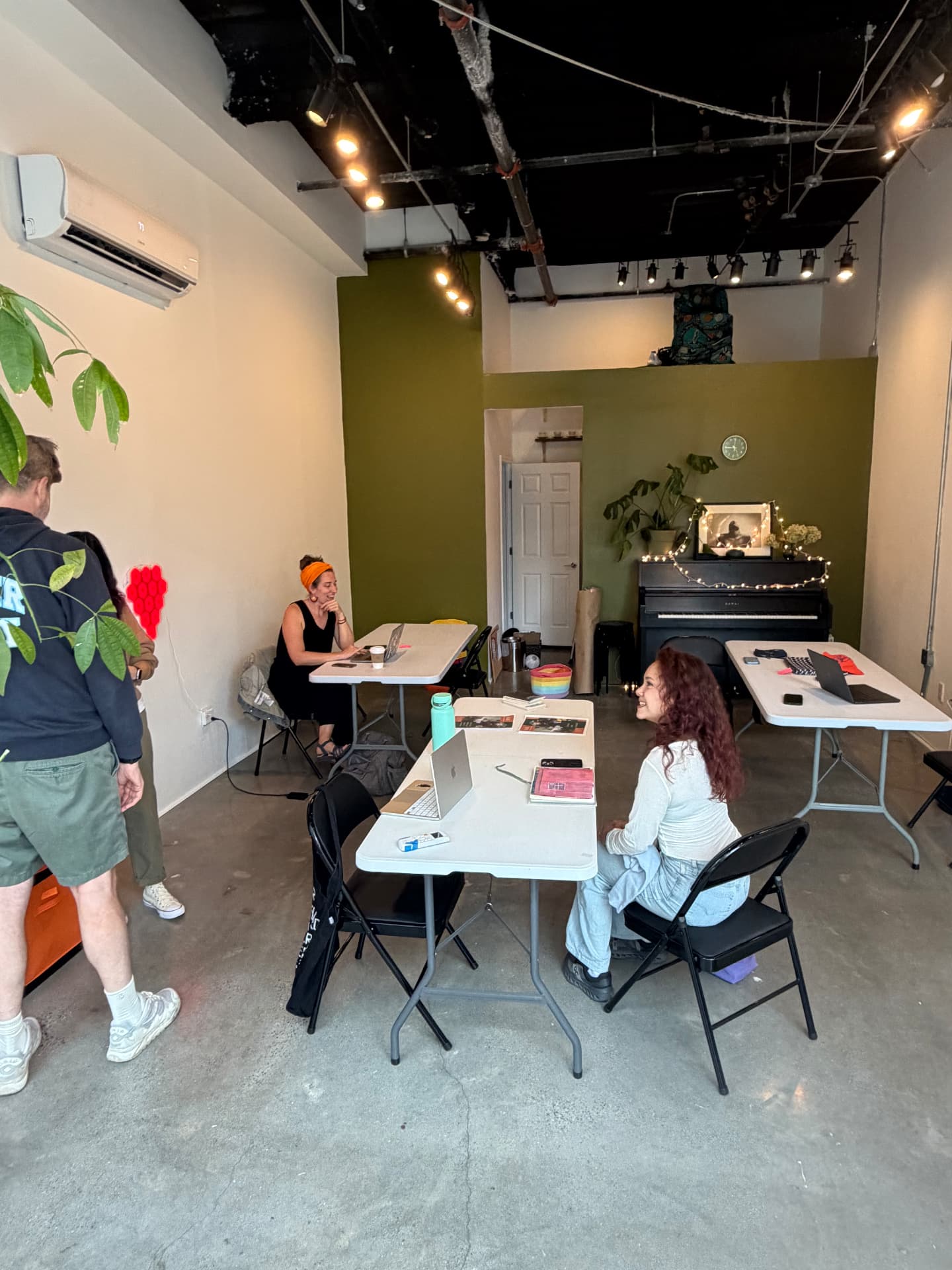 Co-working at RISE: neighbors working and chatting at shared tables near the piano